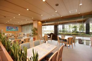a dining room with tables and chairs and windows at Hotel Hamatsu in Koriyama