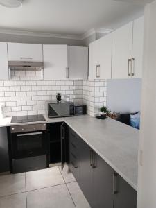 een keuken met witte kasten en een zwart apparaat bij Da Gama Villa in Marina da Gama