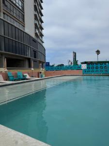 a swimming pool with blue chairs next to a building at Modern 2BR Ocean View Pool & Kids Area CheckIn 2PM in Tijuana
