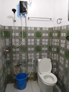a bathroom with a toilet and a shower and a bucket at Nanay Bebs Guesthouse in General Luna
