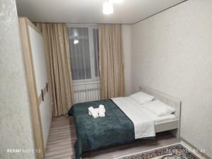 a bedroom with a bed with two towels on it at Мирный дом in Astana