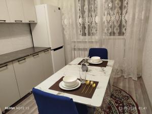 a kitchen with a table with plates and glasses on it at Мирный дом in Astana