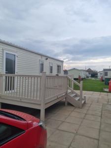 a mobile home with a deck and a house at Coop129 Golden sands holiday park in Kinmel Bay