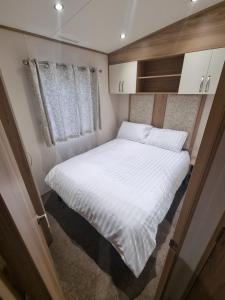 a small bedroom with a white bed in an rv at Coop129 Golden sands holiday park in Kinmel Bay