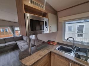 an rv kitchen with a sink and a microwave at Coop129 Golden sands holiday park in Kinmel Bay +4 photos