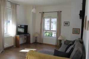 a living room with a couch and a television at La Belle Escale, appartement calme, avec parking, Aix-les-Bains in Aix-les-Bains