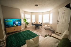 a living room with a couch and a tv and a table at Stylish & Cozy Retreat with Backyard & Parking in Charlotte
