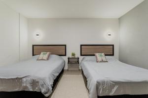 two beds in a room with white walls at CASA NAMI- Cancún Beachside Suites in Cancún