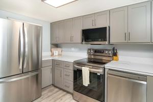 une cuisine avec des appareils en acier inoxydable et des armoires blanches dans l'établissement Pier Point South Oceanfront Townhouse Condo E-60, à Saint Augustine Beach