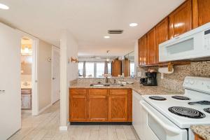une cuisine avec des armoires en bois et un four blanc dans l'établissement Pier Point South Oceanfront Townhouse Condo A-6, à Saint Augustine Beach