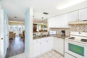 a kitchen with white cabinets and a living room at Pier Point South Ocean View Condo B-18 in Saint Augustine Beach