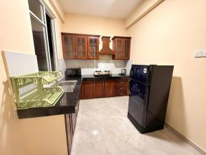 a kitchen with a black refrigerator and wooden cabinets at Wellness Residencies in Colombo