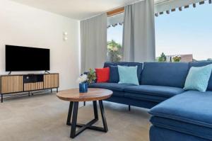 a living room with a blue couch and a tv at Penthouse Panorama Deluxe - Seesicht - BBQ - Beach Paradise - Loft Premium in Öhningen