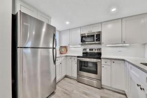 a kitchen with white cabinets and a stainless steel refrigerator at Pier Point South Ocean View Condo D-44 in Saint Augustine Beach