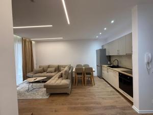 a living room with a couch and a table and a kitchen at Univers City Apartment in Tirana