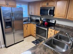 a kitchen with stainless steel appliances and wooden cabinets at Pier Point South Oceanfront Condo A-1 in Saint Augustine Beach