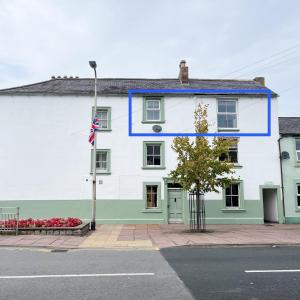 a white and green building with a flag on it at Borders Retreat, Cosy 1 Bed Flat - 3miles from M6 Jct45 - near A75, Gretna & Carlisle in Longtown