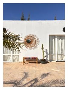 a bench in front of a white wall with a mirror at Villa Habiba - Superbe maison avec piscine chauffée à Ghazoua in Ghazoua