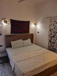 a bed in a bedroom with two lights on the wall at Beat Mousa in Dahab