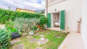 un jardin devant un bâtiment blanc aux volets verts dans l'établissement Casa Bella vista, à Vallecchia