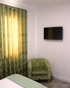 a bedroom with a chair and a television on a wall at AquaChaves Apart Studios in Chaves