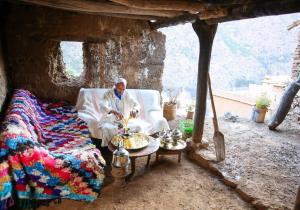 un hombre sentado en un sofá en una habitación con una mesa en Adrar view lodge, en Imlil