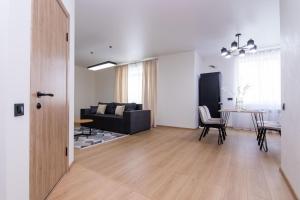 Una sala de estar con un sofá negro y una mesa. en Prime Business Apartments Cherkaska, en Petropavlovskaya Borshchagovka