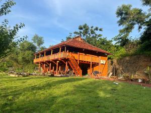 a large wooden house with a grass field in front of it at MK Home in Lương Sơn
