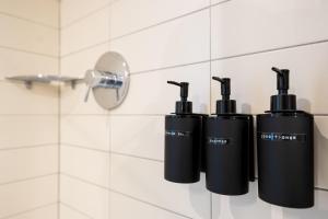 Un grupo de tres botellas negras en una pared de un baño. en Embassy Studio 303, en Vilna