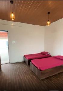 two beds in a room with pink sheets at The Sol Street Villa in Nashik +16 photos