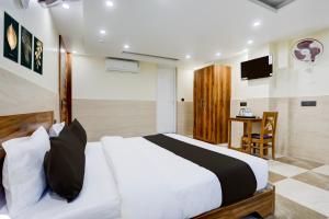 a bedroom with a bed and a desk and a television at Collection O Elite in Dehradun +26 photos