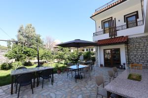 een terras met tafels, stoelen en een parasol bij Villa Starova in Berat