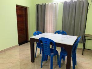 a dining room table with blue chairs around it at Serene Retreat in Varkala