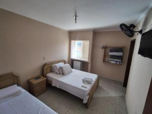 a small room with two beds and a television at Niv's Hotel in Monte Sião