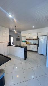 a large kitchen with white tile floors and a refrigerator at Casa temporada Guarapari in Guarapari