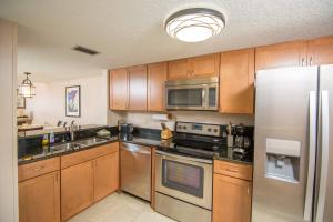 a kitchen with wooden cabinets and stainless steel appliances at Pier Point South Oceanfront Townhouse Condo A-3 in Saint Augustine Beach