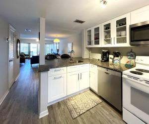 a kitchen with white cabinets and a living room at Pier Point South Ocean View Townhouse Condo D-49 in Saint Augustine Beach