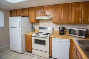 a kitchen with white appliances and wooden cabinets at Pier Point South Oceanfront Townhouse Condo A-8 in Saint Augustine Beach