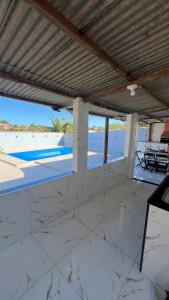 an empty patio with a table and chairs under a roof at Casa temporada Guarapari in Guarapari