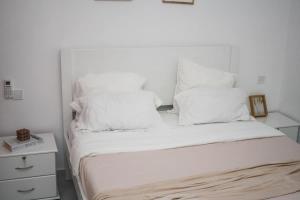 een wit bed met witte lakens en kussens bij Apartment Morabeza in Praia Cidadela in Praia