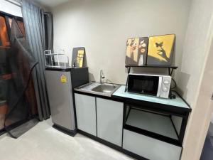 a small kitchen with a sink and a microwave at Secret Pastel Room Laksi Donmuang Airport ห้องลับพาสเทลหลักสี่สนามบินดอนเมือง in Lak Si