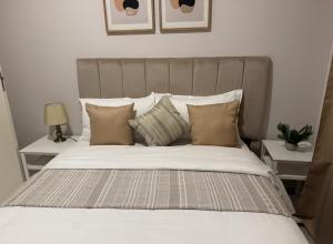 a large bed with white sheets and pillows at The Fig Central Apartments in Gaborone