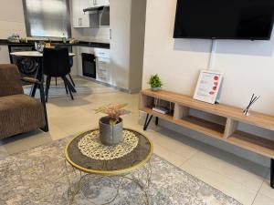 a living room with a table and a tv on a wall at The Fig Central Apartments in Gaborone