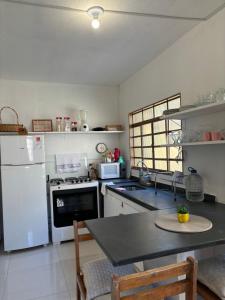 a kitchen with white appliances and a black counter top at Casa Cantinho Encantado, próximo ao Centro de Passa Quatro in Passa Quatro