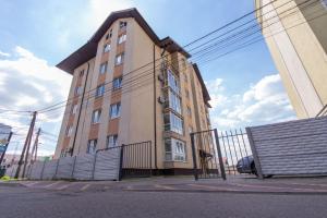 un edificio alto con una valla delante en Prime Business Apartments Cherkaska, en Petropavlovskaya Borshchagovka