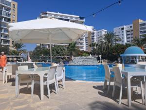 a table and chairs with an umbrella next to a swimming pool at Fabius 12 Caesars Resort & Spa in Iskele