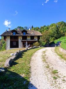 a house on a hill next to a dirt road at Maso Tre Cucù by Go New Location in Cavalese