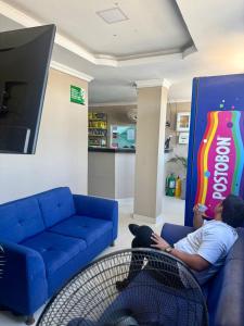 a man sitting on a couch in front of a coke cola sign at hotel gloria del norte sas in Cartagena de Indias