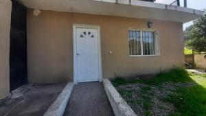 a house with a white door and a window at Apart Sierras Chicas in Río Ceballos