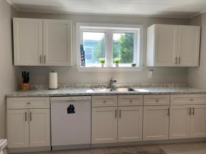 a kitchen with white cabinets and a sink and two windows at Mariners Nest in Saint John